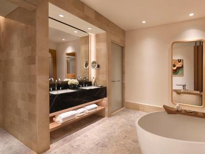 Moderne Badezimmer mit freistehender Badewanne, großer Spiegel und begehbarer Dusche in Beige- und Brauntönen.