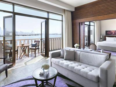 Helles Wohnzimmer mit grauem Sofa, Glastisch und Balkon mit Stadtblick bei Tageslicht.