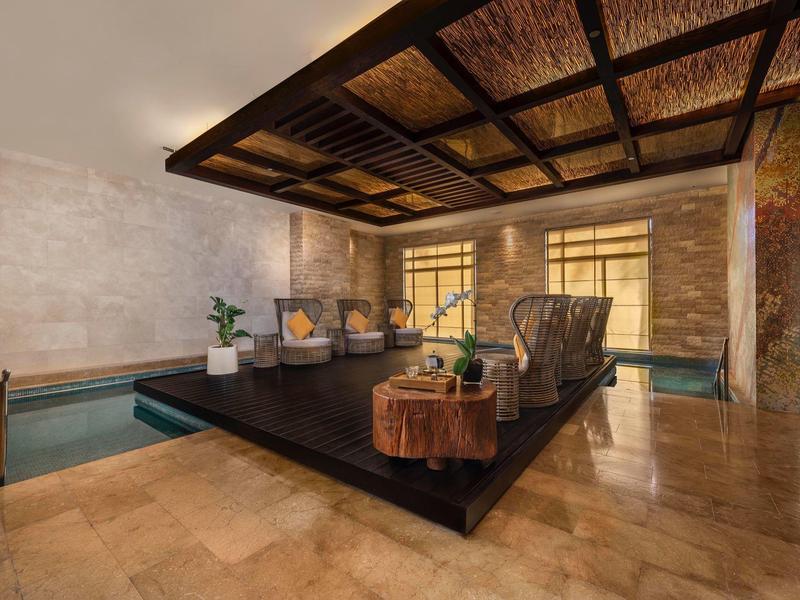 Moderner Wellnessraum mit bequemer Sitzinsel, Wasserbecken und warmem, natürlichem Licht.