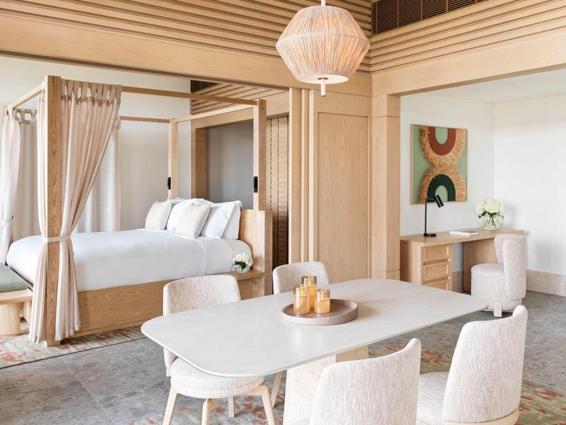 Helles Schlafzimmer mit Baldachinbett, weißem Tisch, Stühlen und moderner Wanddekoration.