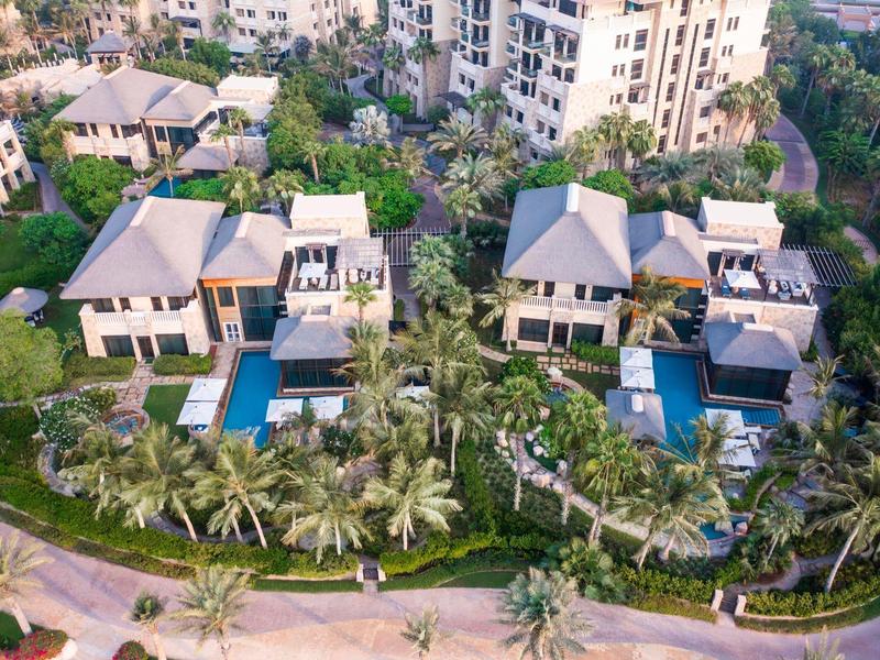 Luftaufnahme von zwei großen Villen mit Pools, umgeben von begrünten Gärten und Palmen.