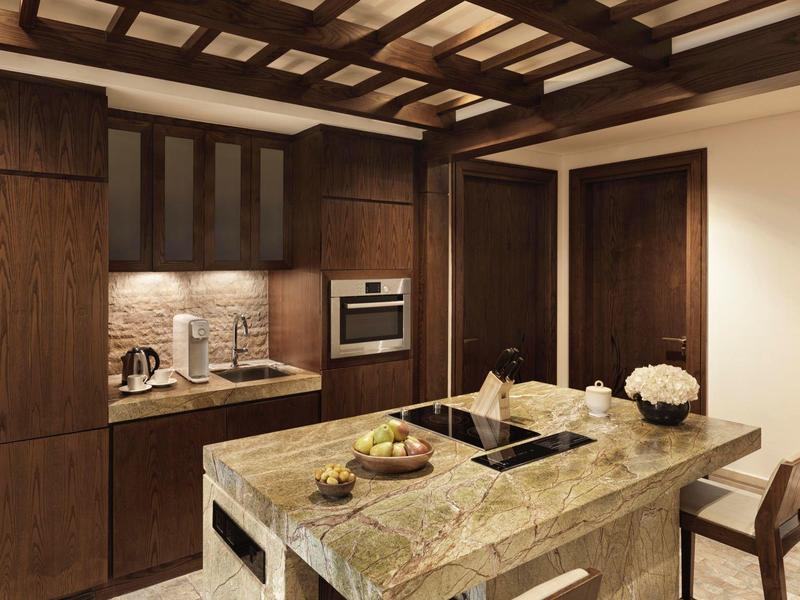 Moderne Küche mit dunklem Holz, grauer Arbeitsplatte und eingebautem Ofen. Holzdecke mit Balken.