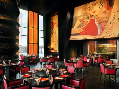 Ristorante elegante in hotel con sedie rosse, tavoli rotondi e grandi murales colorati.