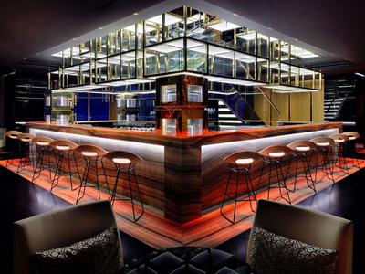 Bar dell'hotel moderno con sgabelli eleganti e illuminazione indiretta in un ambiente elegante.