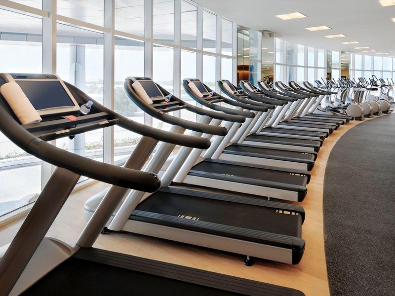 Nowoczesne bieżnie w jasnej siłowni hotelowej.