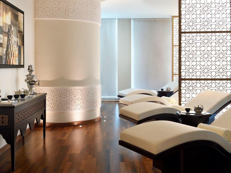 Eleganckie wnętrze spa lub pokoju wypoczynkowego z leżakami i ozdobną drewnianą szafką.