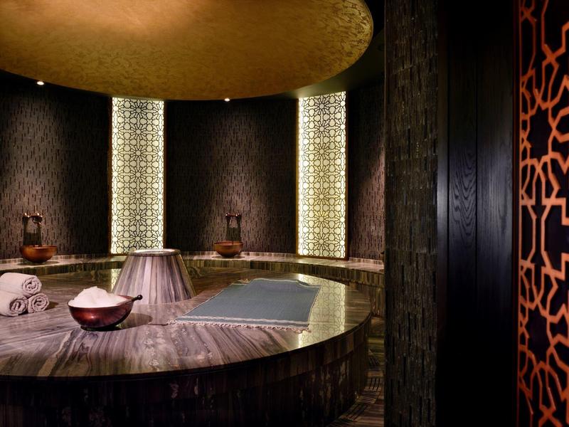 Elegancka strefa spa z okrągłym stołem do masażu i ciepłym, nastrojowym światłem.