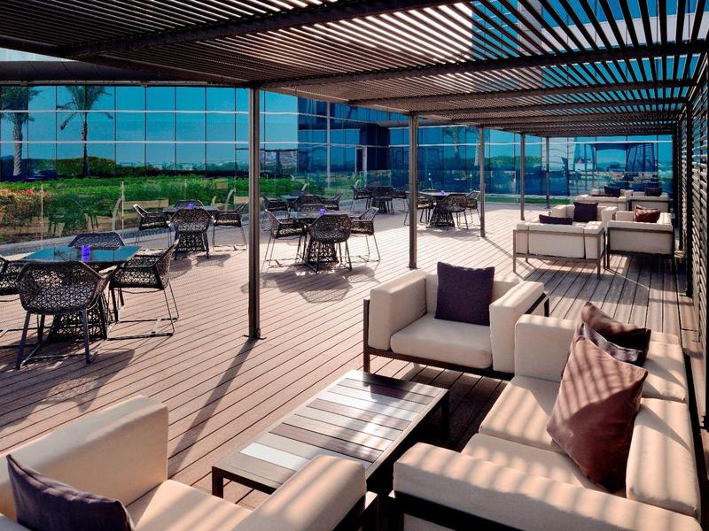 Przestronny taras hotelowy z nowoczesnymi miejscami do siedzenia i pergolą przeciwsłoneczną.