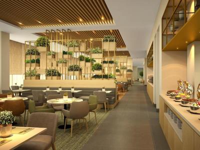 Modern hotel restaurant area with buffet, tables, and green plants as decoration.