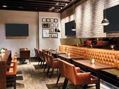 Moderně zařízená hotelová jídelna s hnědými koženými židlemi a dřevěnými stoly.