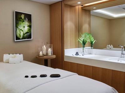 Modern wellness room with massage table, candles, and large sink.