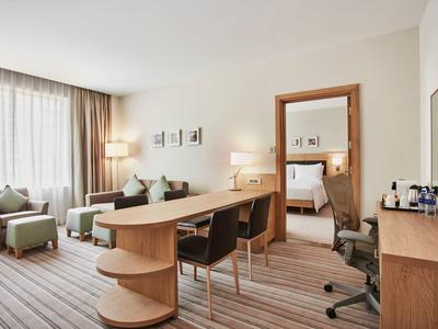 Modern hotel room with desk, chairs, and large window with curtains.