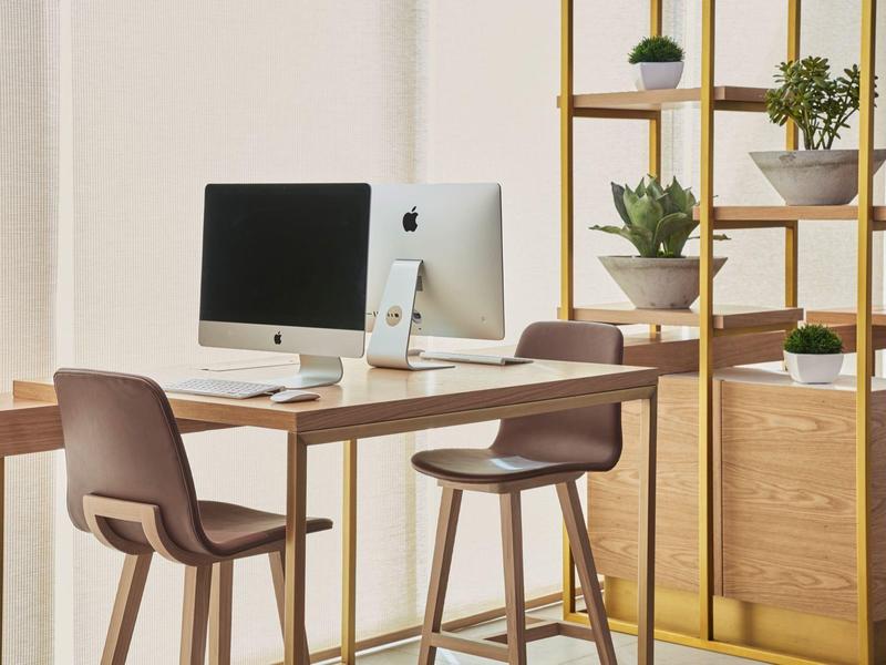 Modern workspace with a computer and two chairs next to a shelf with plants.