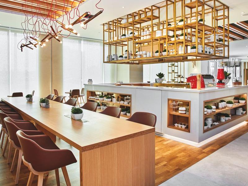 Modern hotel lounge area with a long wooden table and comfortable chairs.