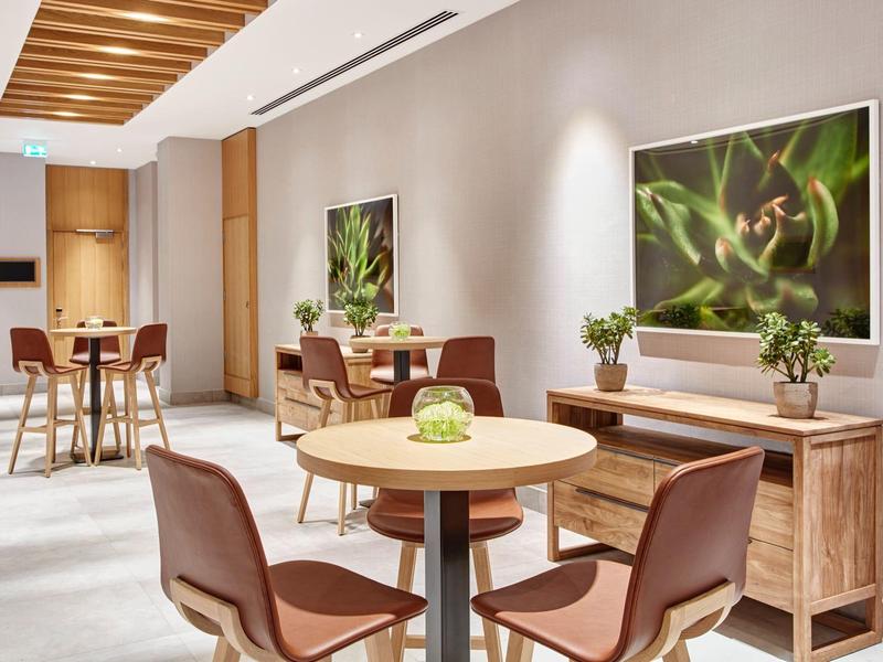 Modern seating area with round tables, comfortable chairs, and nature pictures on the wall.