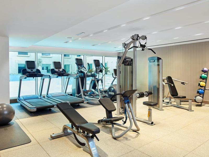 Bright gym with modern equipment and large windows showing a city view.
