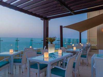 Terrasse du soir avec tables dressées et vue sur la mer au crépuscule.