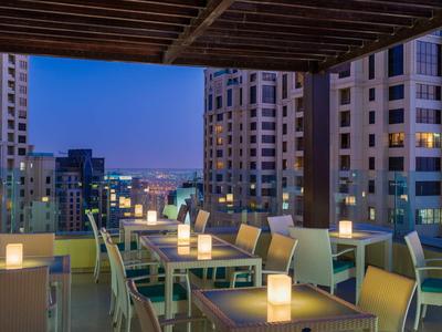 Abendliche Dachterrasse mit Tischen, Stühlen und beleuchteten Laternen in einem Hotel.