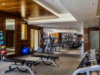 Moderner Fitnessraum mit Geräten, Gewichten und Holzdecke in einem Hotel.