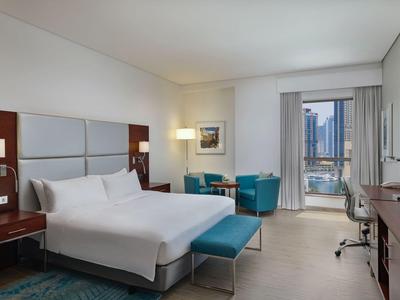 Modernes Hotelzimmer mit großem Bett, Sitzbereich und Blick auf die Stadt.