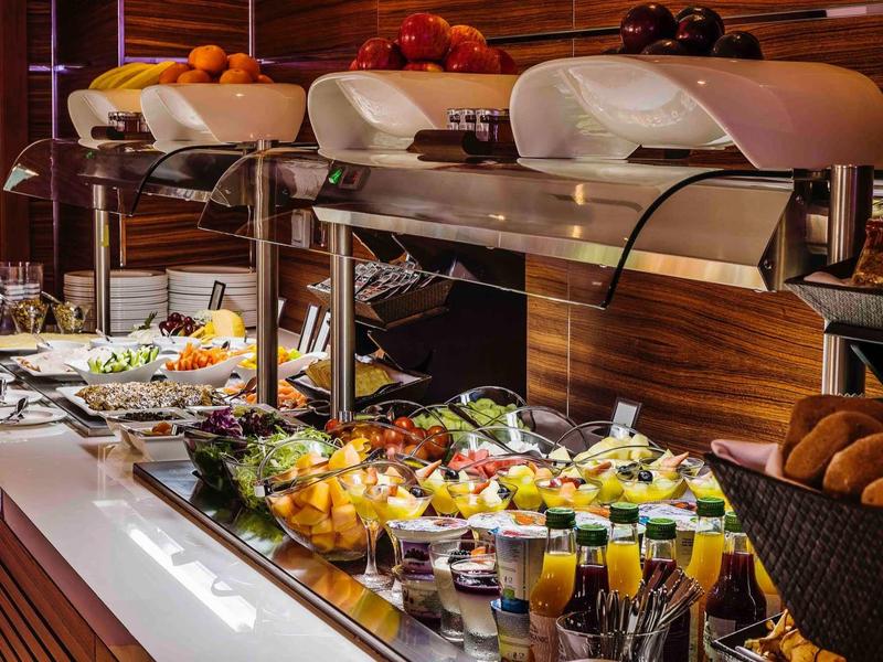 Buffet avec fruits frais, légumes, jus et produits de boulangerie dans un restaurant d'hôtel.