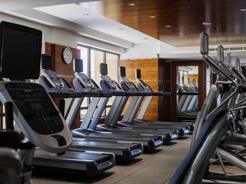 Salle de sport moderne avec une rangée de tapis de course et d'appareils d'exercice dans un hôtel.