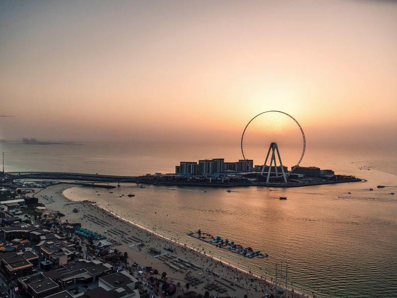 Vue sur une ville côtière avec une grande roue au coucher du soleil