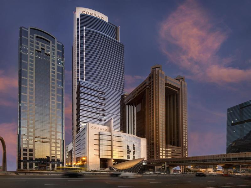 Moderne Hochhäuser bei Abenddämmerung mit reflektierenden Glasfassaden und lila-orangefarbenem Himmel.