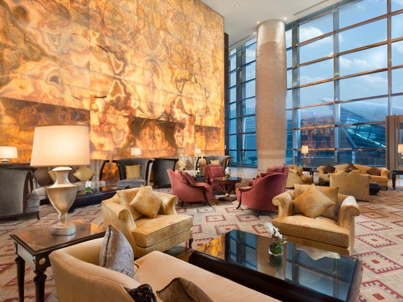 Luxuriöser Lounge-Bereich mit bequemen Sesseln, großen Fenstern und warm beleuchteter Marmorwand.