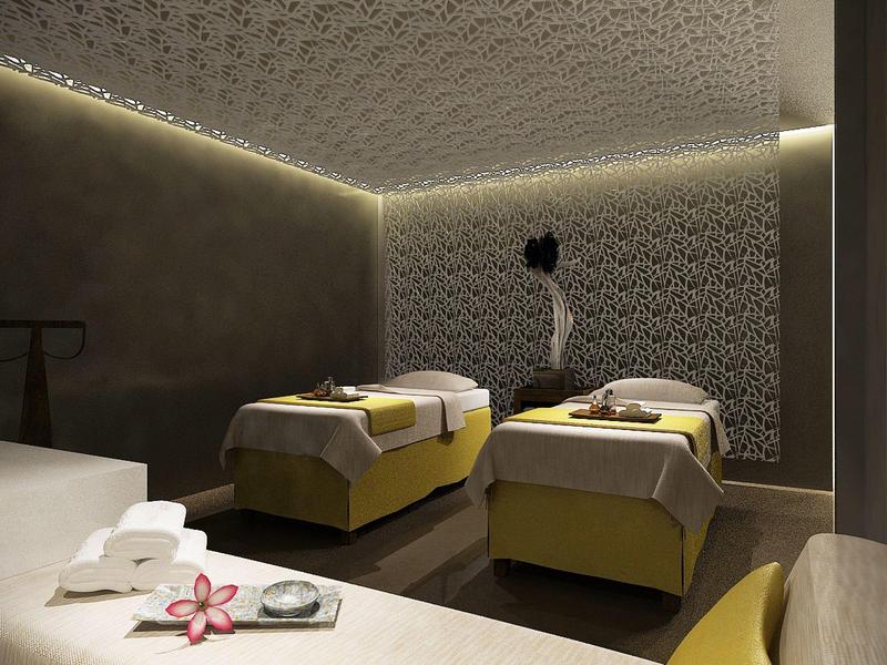 Raum mit zwei gelben Massageliegen, gedämpftem Licht und dekorativer Wandbeleuchtung.