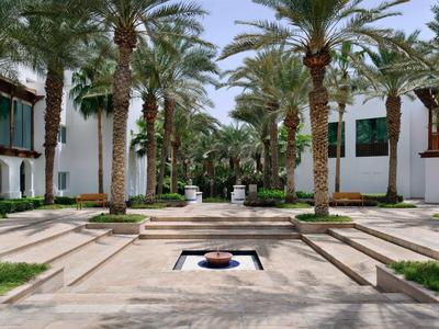 Osoba odpaluje na golfovém hřišti při západu slunce s palmami v pozadí.