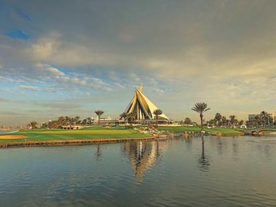 Nábreží s výraznou velkou budovou a stromy pod zamračenou oblohou.