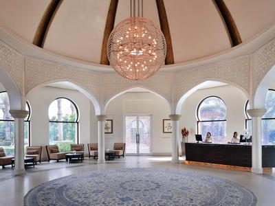 Spacious hotel lobby with architectural arches, round carpet, and impressive chandelier.