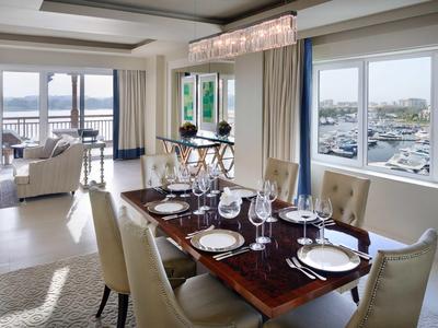 Moderní hotelový pokoj s manželskou postelí, dřevěnou podlahou a výhledem na zahradu a bazén.