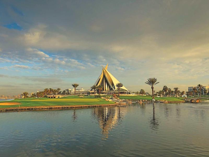 Nábreží s výraznou velkou budovou a stromy pod zamračenou oblohou.