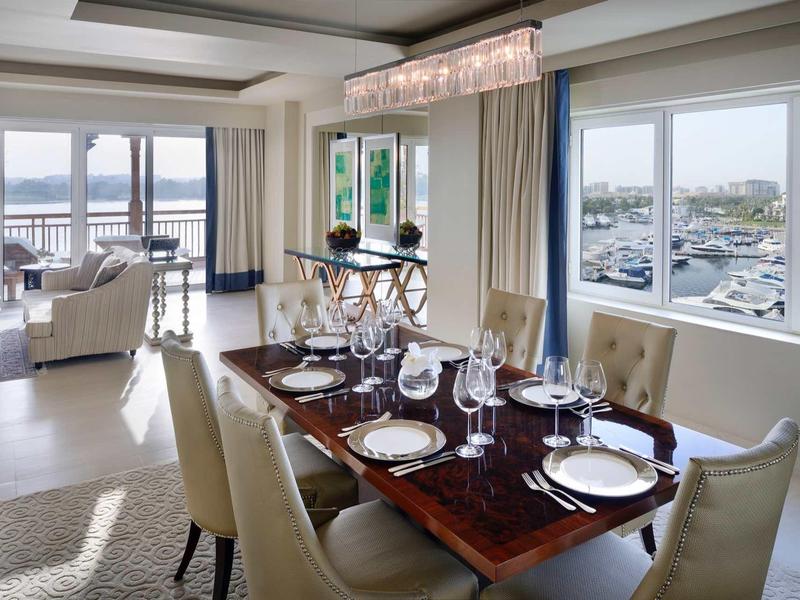 Moderní hotelový pokoj s manželskou postelí, dřevěnou podlahou a výhledem na zahradu a bazén.