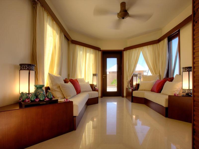 Heller, gemütlicher Hotelraum mit zwei Sofas, Vorhängen und Deckenventilator.