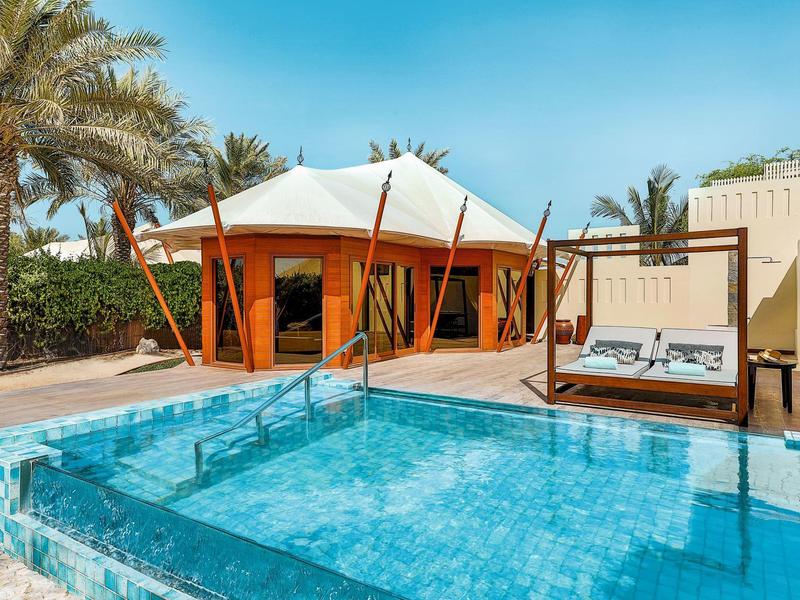 Moderner Poolbereich mit Sonnenterrasse und Pavillon in einer tropischen Hotelanlage.