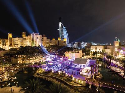 Luxusní noční panorama města s osvětleným moderním hotelem a venkovní akcí.