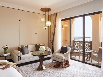 Pohodlný hotelový pokoj s posezením a balkonem s výhledem ven.