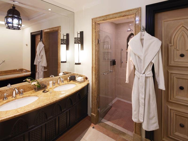 Hotelová koupelna s dvojitou umyvadlem, mramorovou deskou a dvěma bílými župany.