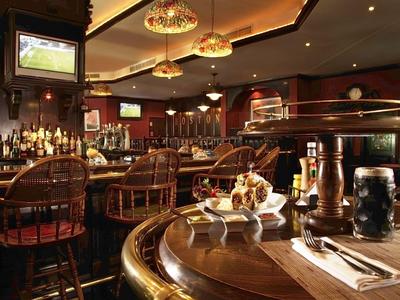 Gemütliche Hotelbar mit Holztheke, Hockern und warmem Licht.