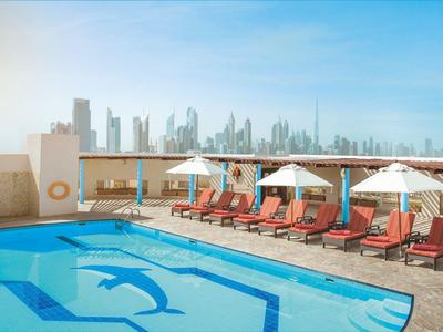 Střešní terasa s bazénem a lehátky s výhledem na panorama města za jasného dne