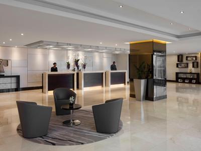 Moderne Hotellobby mit Rezeption und Sitzbereich mit Teppich und Sesseln