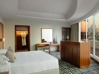 Helle Hotelzimmer mit Doppelbett, Schreibtisch, großem Fenster und Blick auf die Stadt.