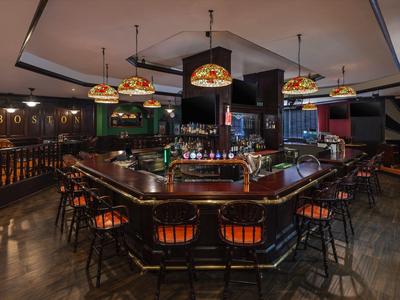 Gemütliche Bar mit hölzernen Theken und bunten Lampen in warmem Licht.