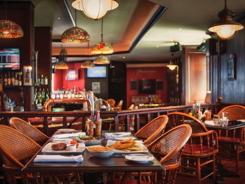 Příjemná restaurace s dřevěným nábytkem a prostřenými stoly v teplém osvětlení.