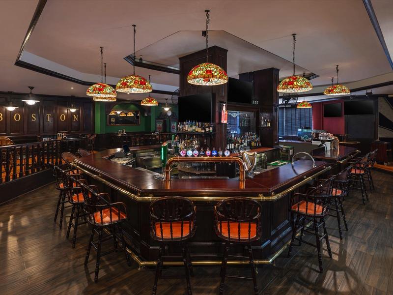 Pohodlný bar s dřevěnými pulty a barevnými lampami v teplém osvětlení.