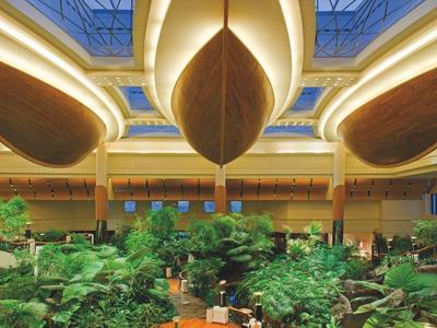 Luxusní hotelový interiér s velkou skleníkem uprostřed a působivým osvětlením.