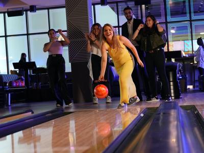 Gruppe von Freunden beim Bowling in einer modernen, gut beleuchteten Bowlingbahn.